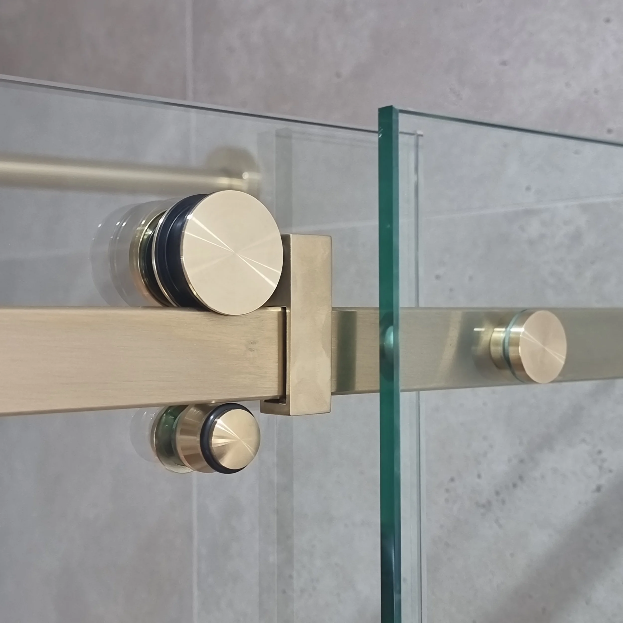 Close-up view of a metallic knob or dial on a light-colored surface, with a glass or plastic panel and a metal or wooden support structure visible in the background.