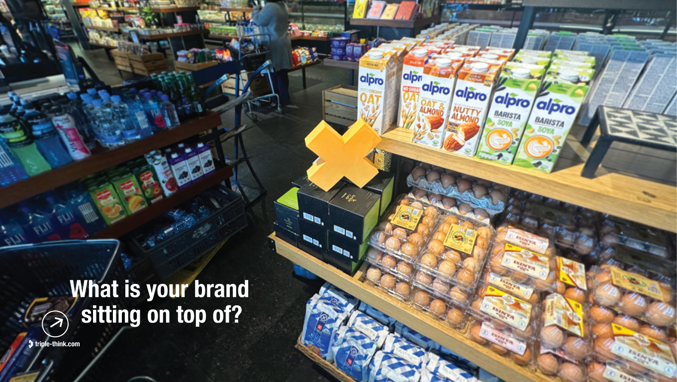 Triple Think Brand Build Order visual showing a full supermarket shelf with a 3D printed letter X, as a reminder that a brand only works once the business beneath it is built.