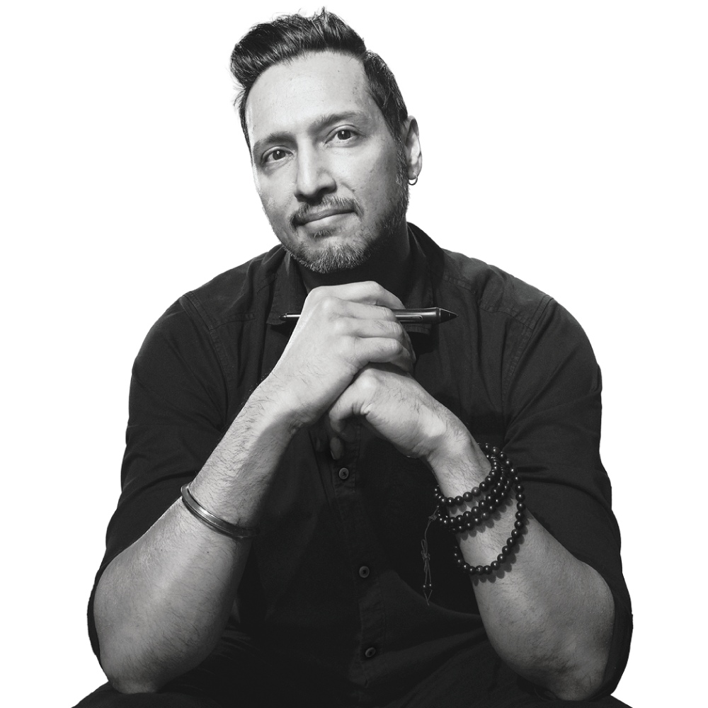 Sandeep Singh Sura, brand strategist and founder of Triple Think, seated with hands clasped, holding a pen. Black and white portrait.
