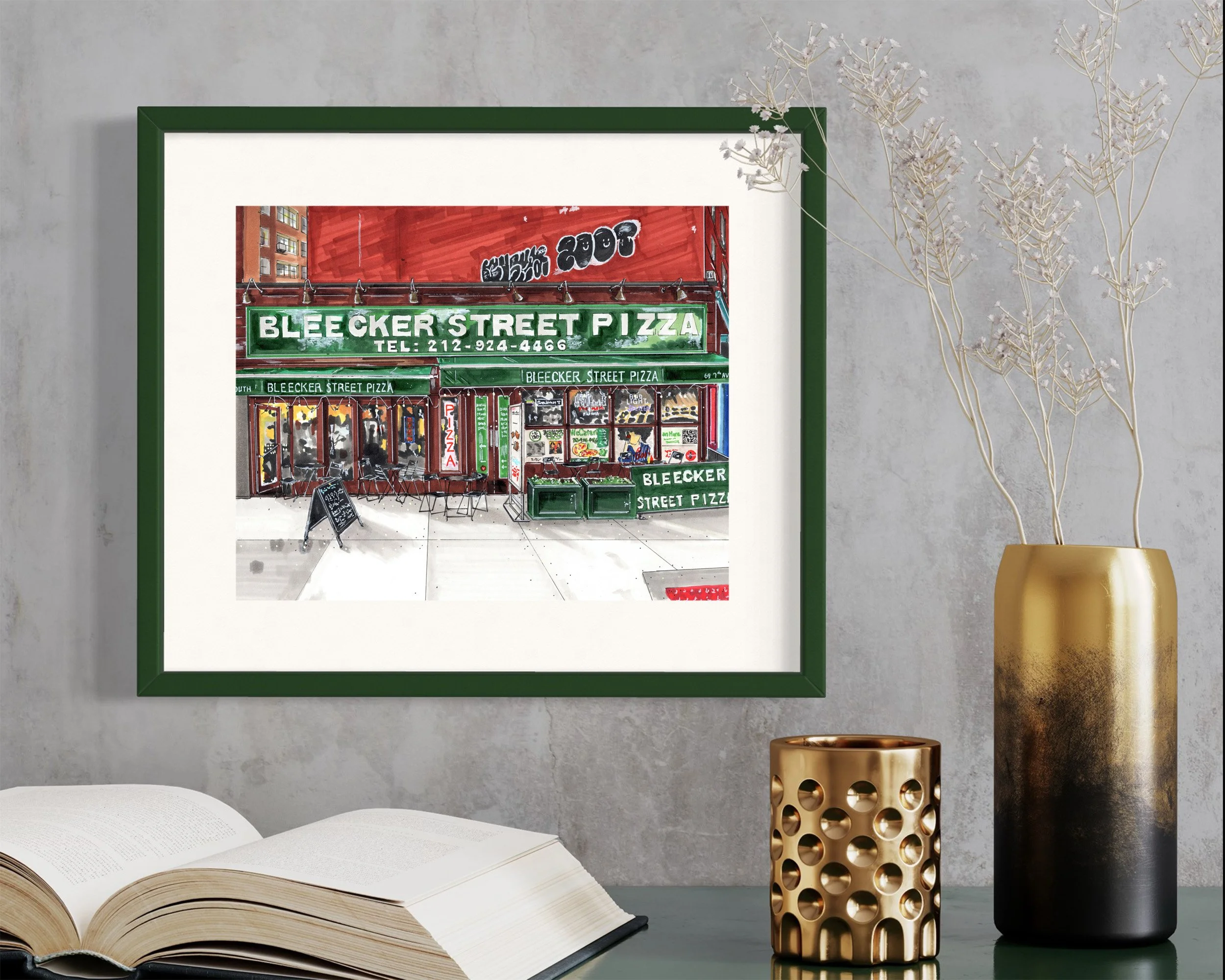 Framed in dark green, this hand-illustrated drawing of Bleecker St Pizza print hangs on the wall