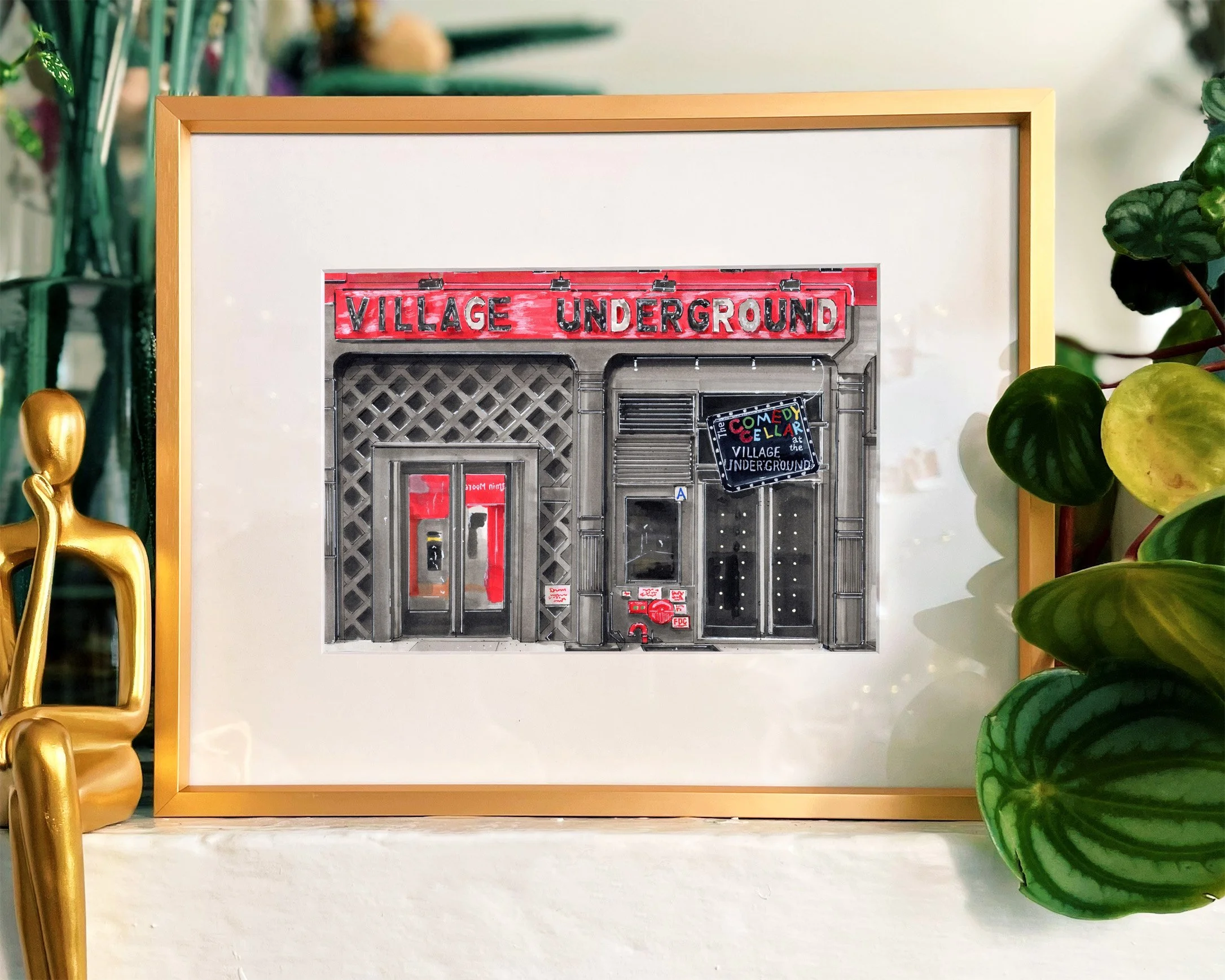 Framed in a gold frame, this hand-illustrated drawing of Comedy Cellar Village Underground print hangs on the wall