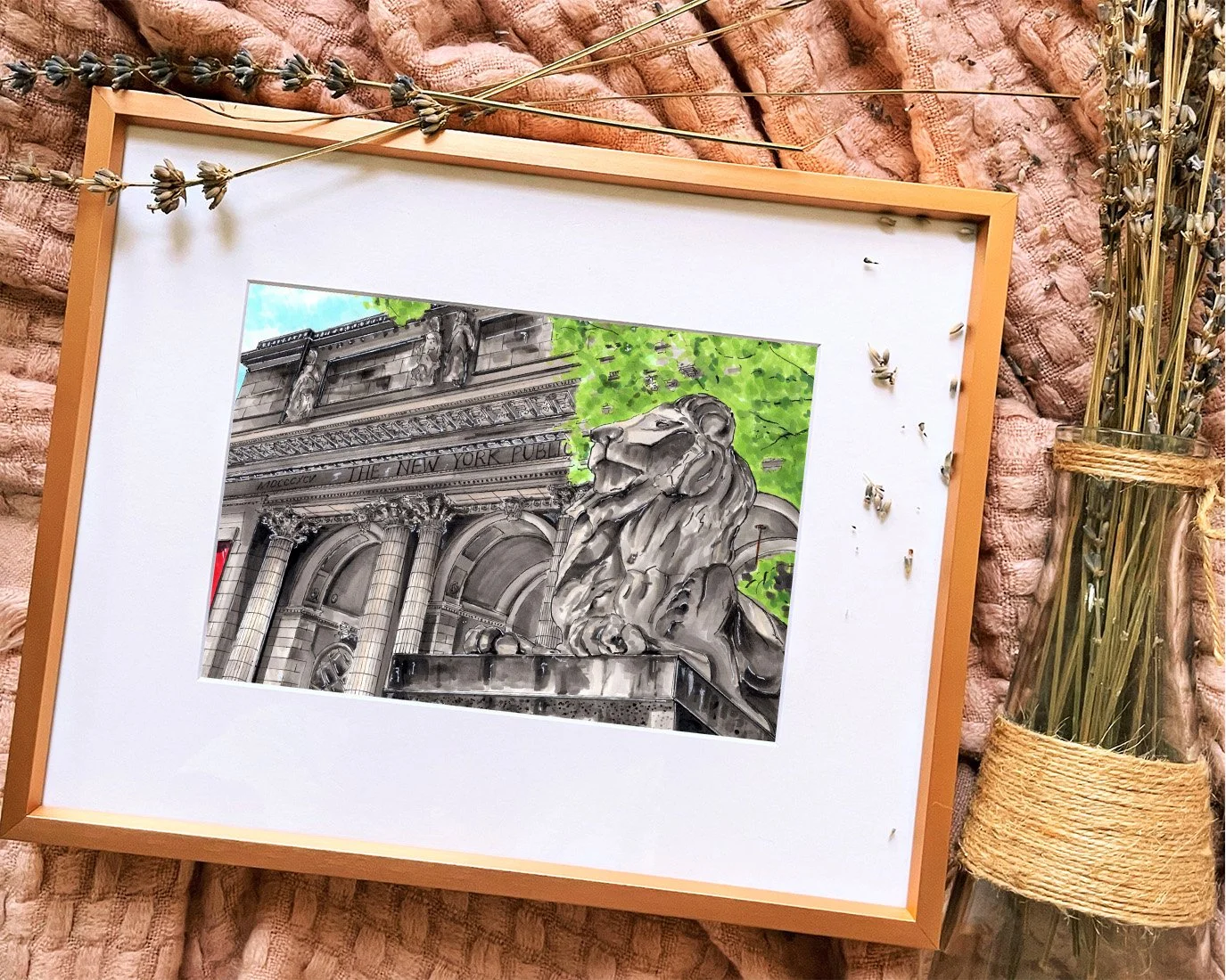 Framed in gold, this hand-illustrated drawing of NYPL Main Building print sits on a pink blanket