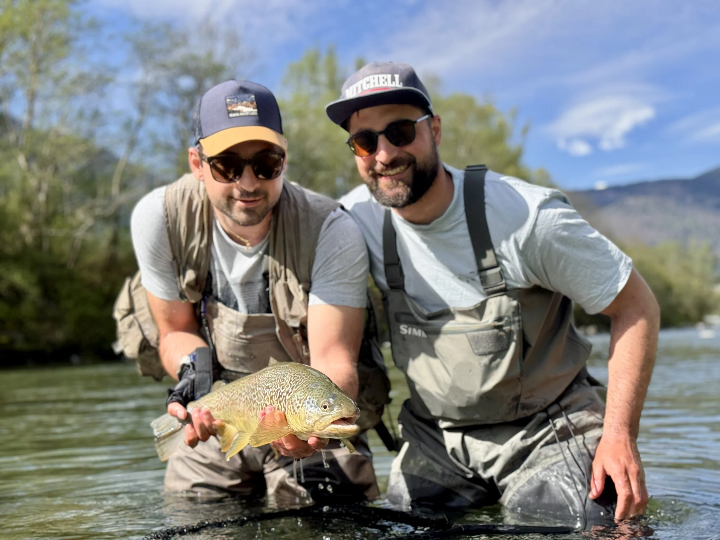 two anglers holding a beautiful marble trout in the dolomites