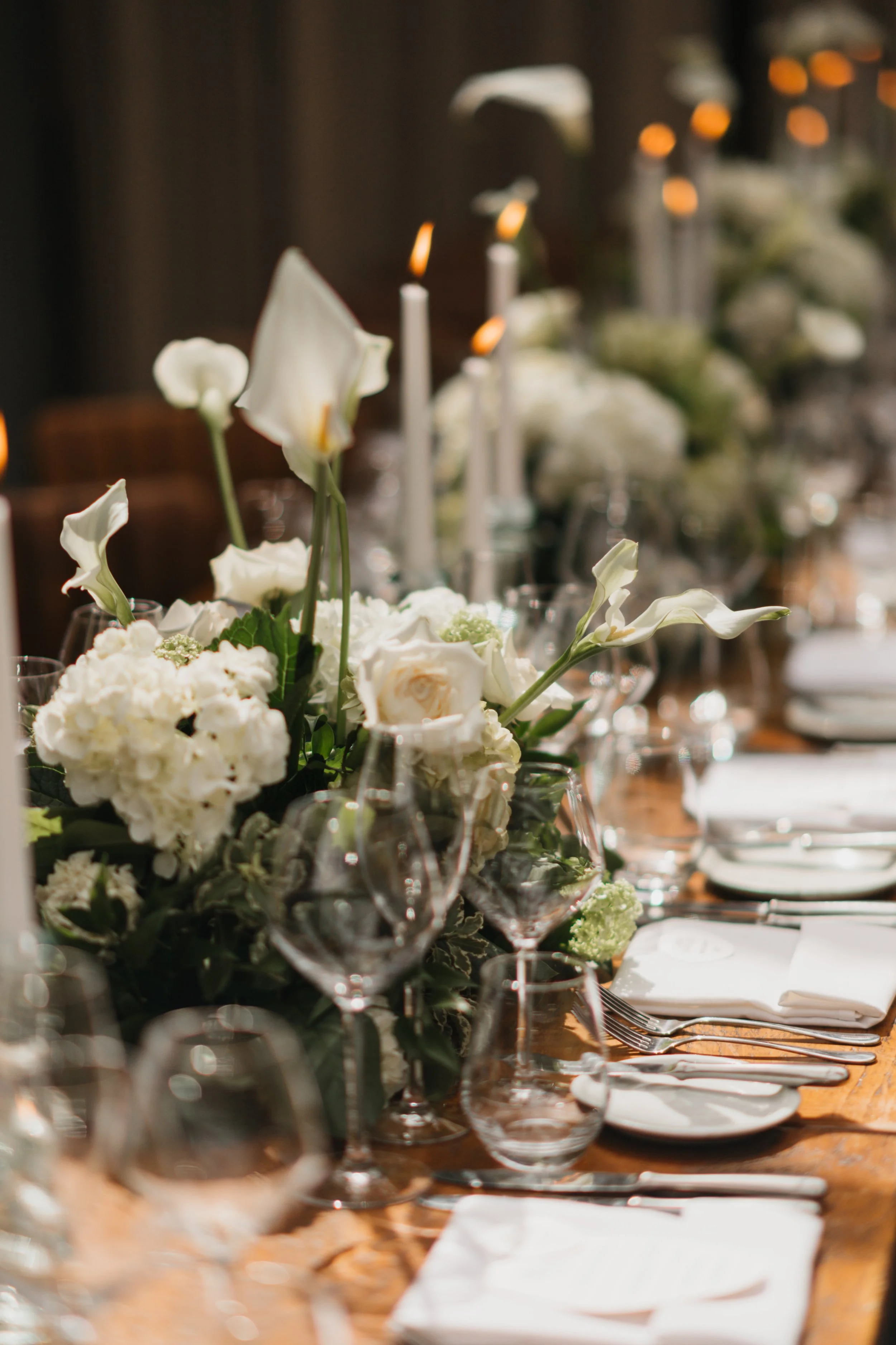 Elegant dining table decorated with white flowers, candles, and glassware for a formal event.