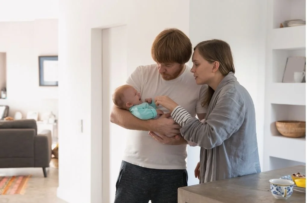 Parents comforting a crying baby together.