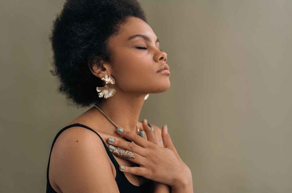 Woman with eyes closed, hand on chest.