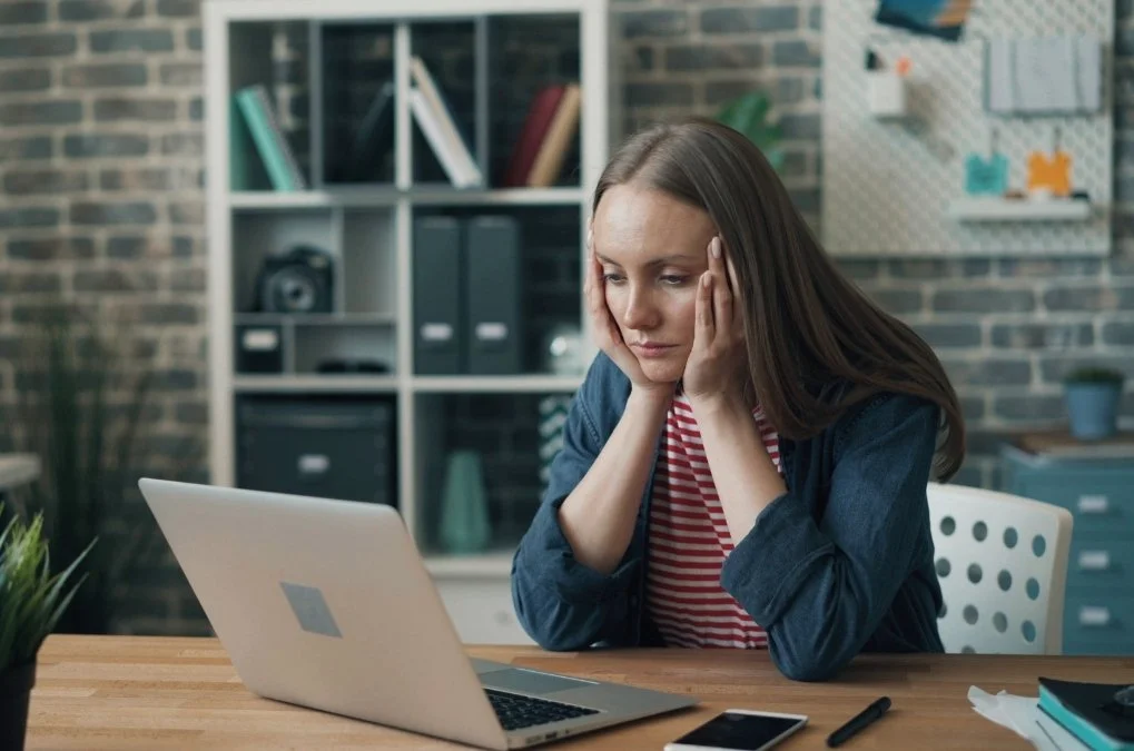 Woman looking stressed at her laptop.