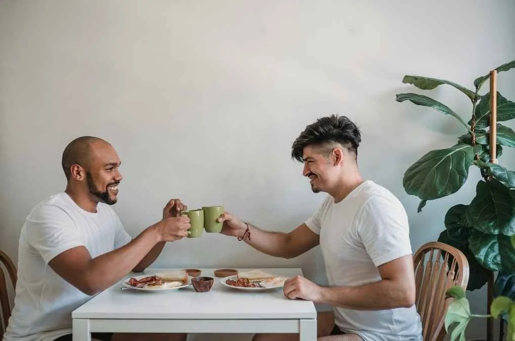 Two men toasting coffee mugs.