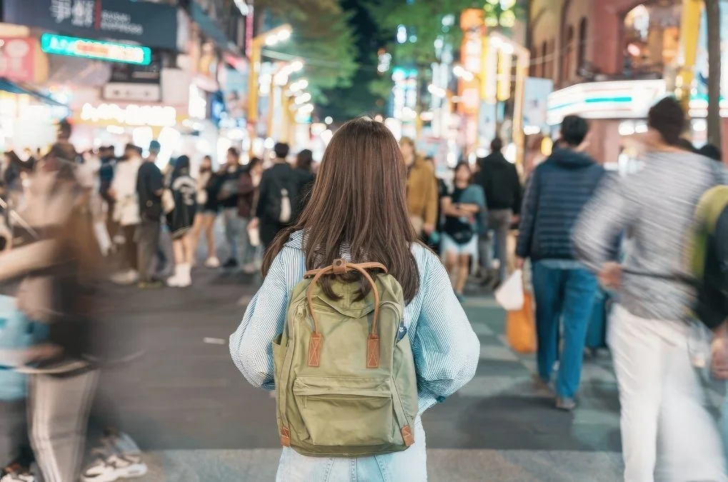 Woman walking alone through a crowded street.