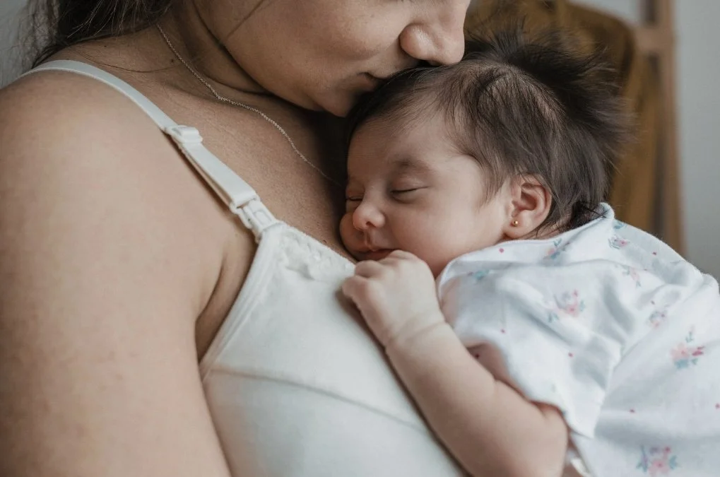 Soft abstract background of mother kissing her sleeping newborn's head. for the section: What can I expect in postpartum therapy?