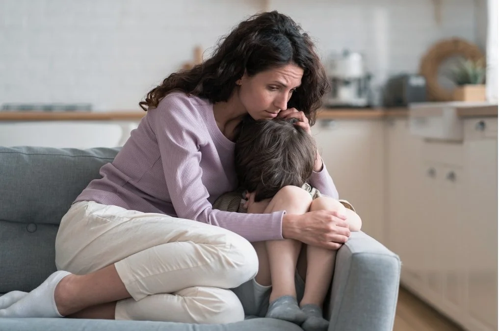 Mother comforting a upset child on the couch.