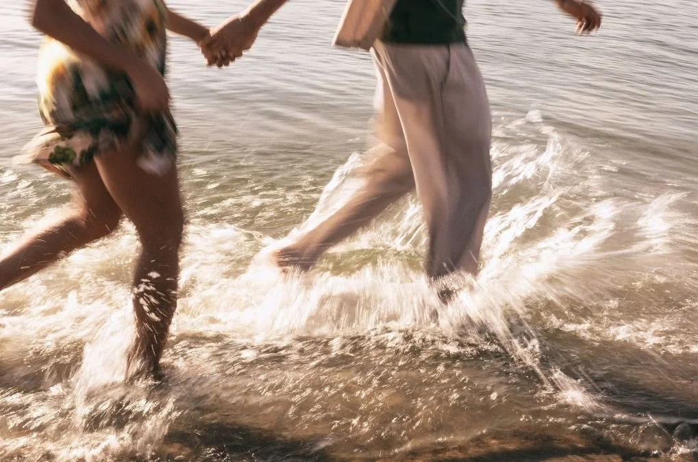 Soft background of couple running hand in hand through water. for the section:  What Can I Expect in Relationship Therapy?