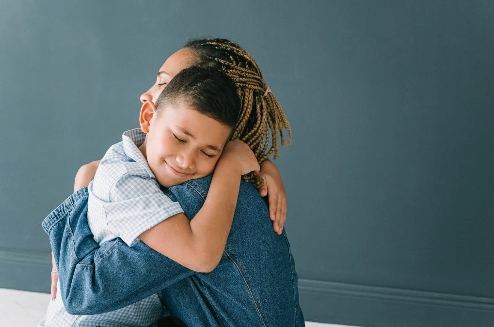 Boy hugging his mother, eyes closed.
