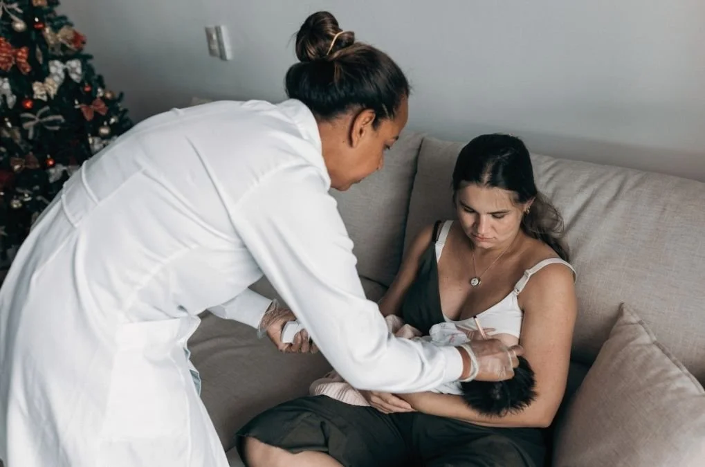 Nurse checking on a mother holding her newborn.