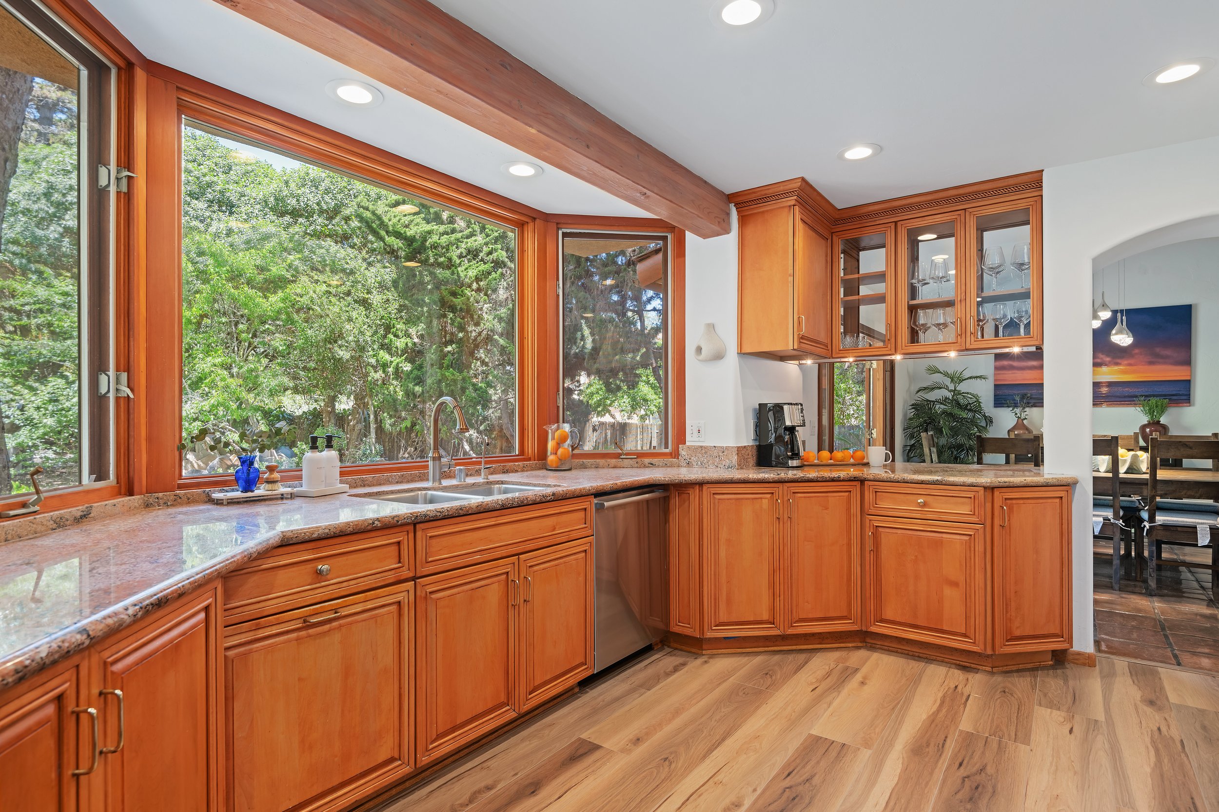 Kitchen with wooden cabinets, granite countertops, and large windows overlooking greenery.