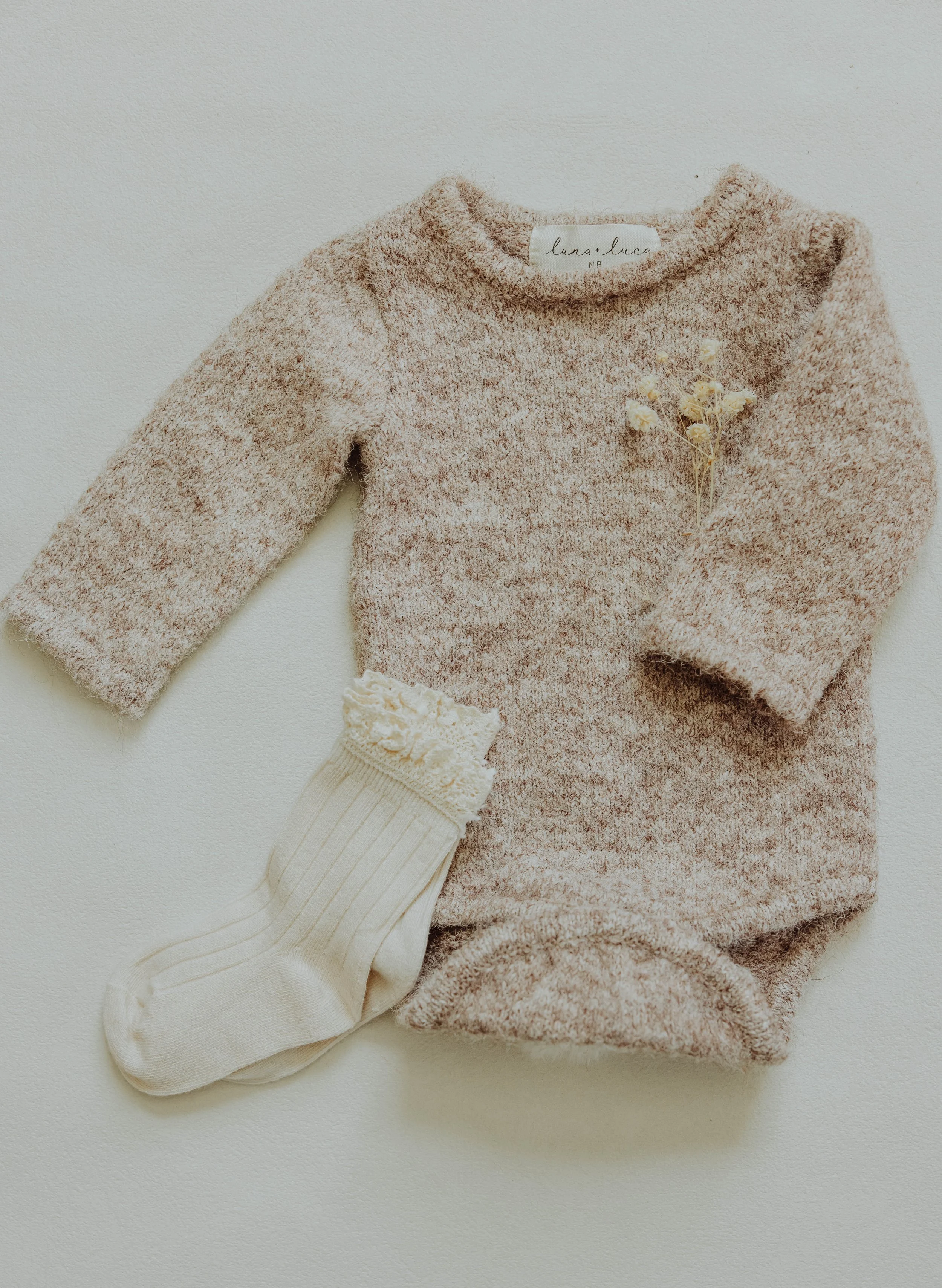   Detail product photo of children's clothing with natural light and textured styling props.  