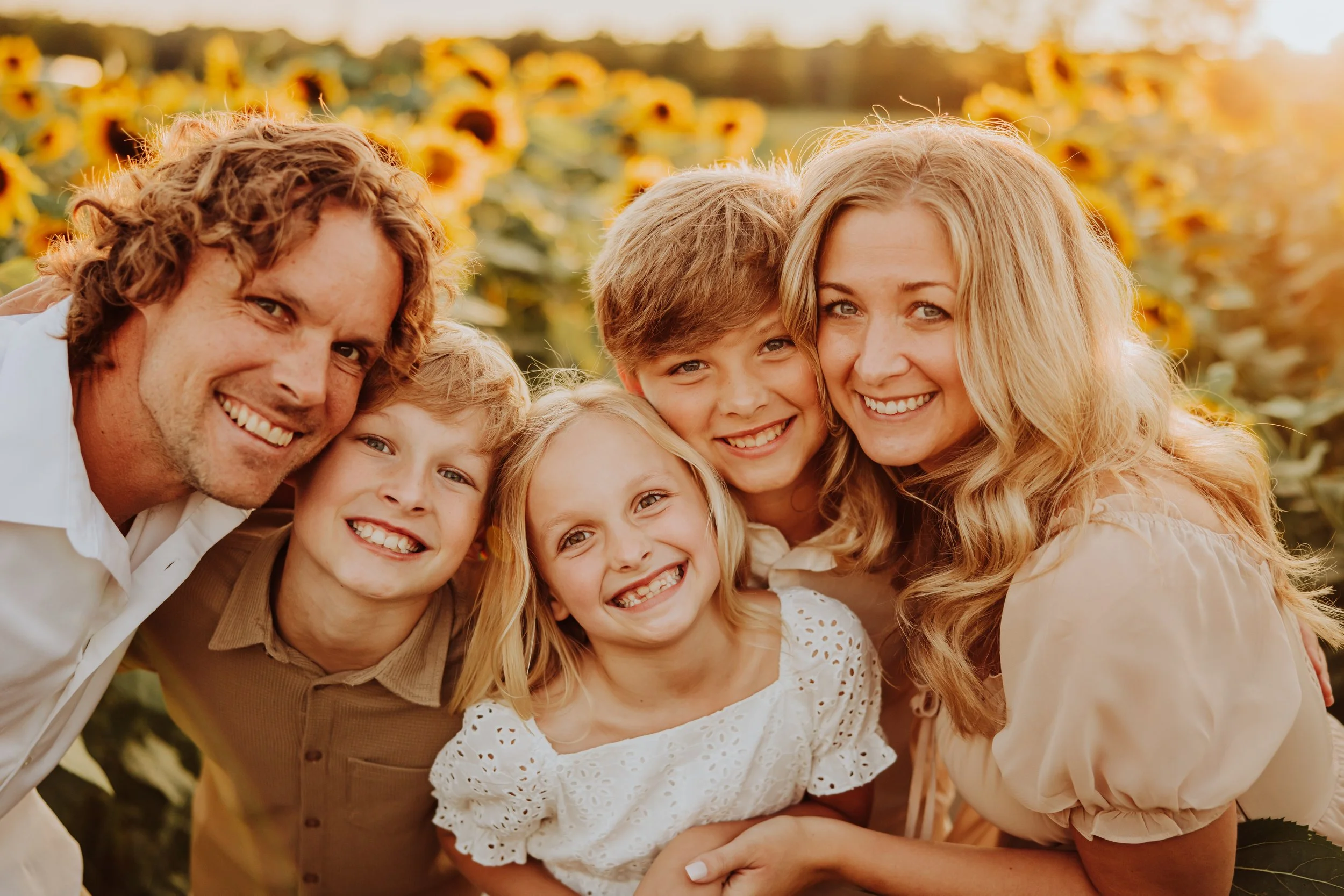Family snuggled together in a sunflower field