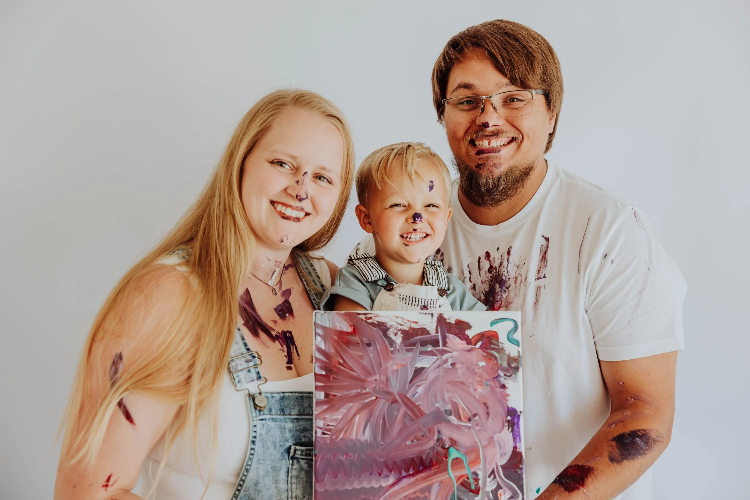 Toddler holding painted canvas from family paint session at Grandville photography studio.