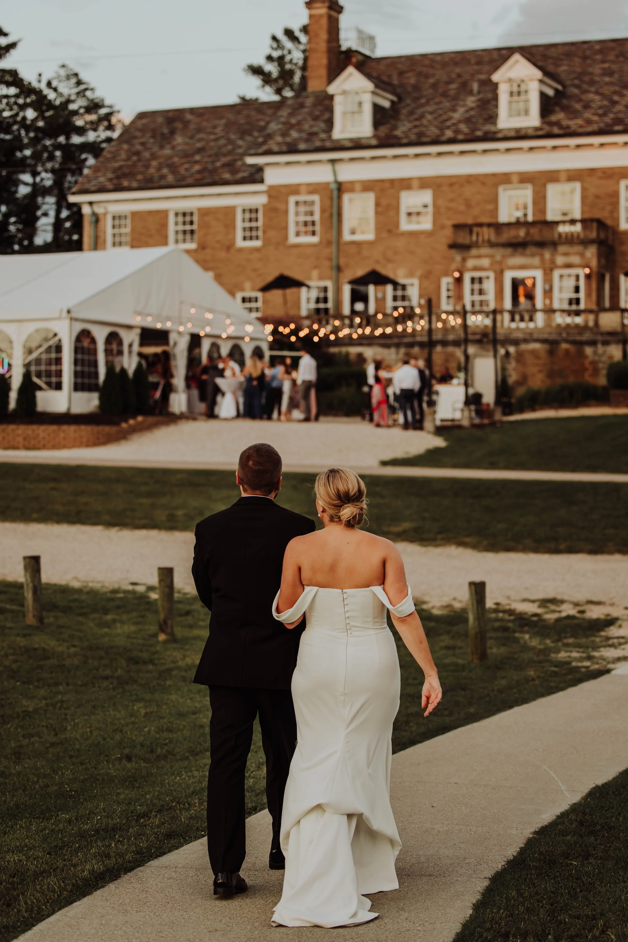 Bride and groom walking toward their tented Felt Mansion Estate wedding reception
