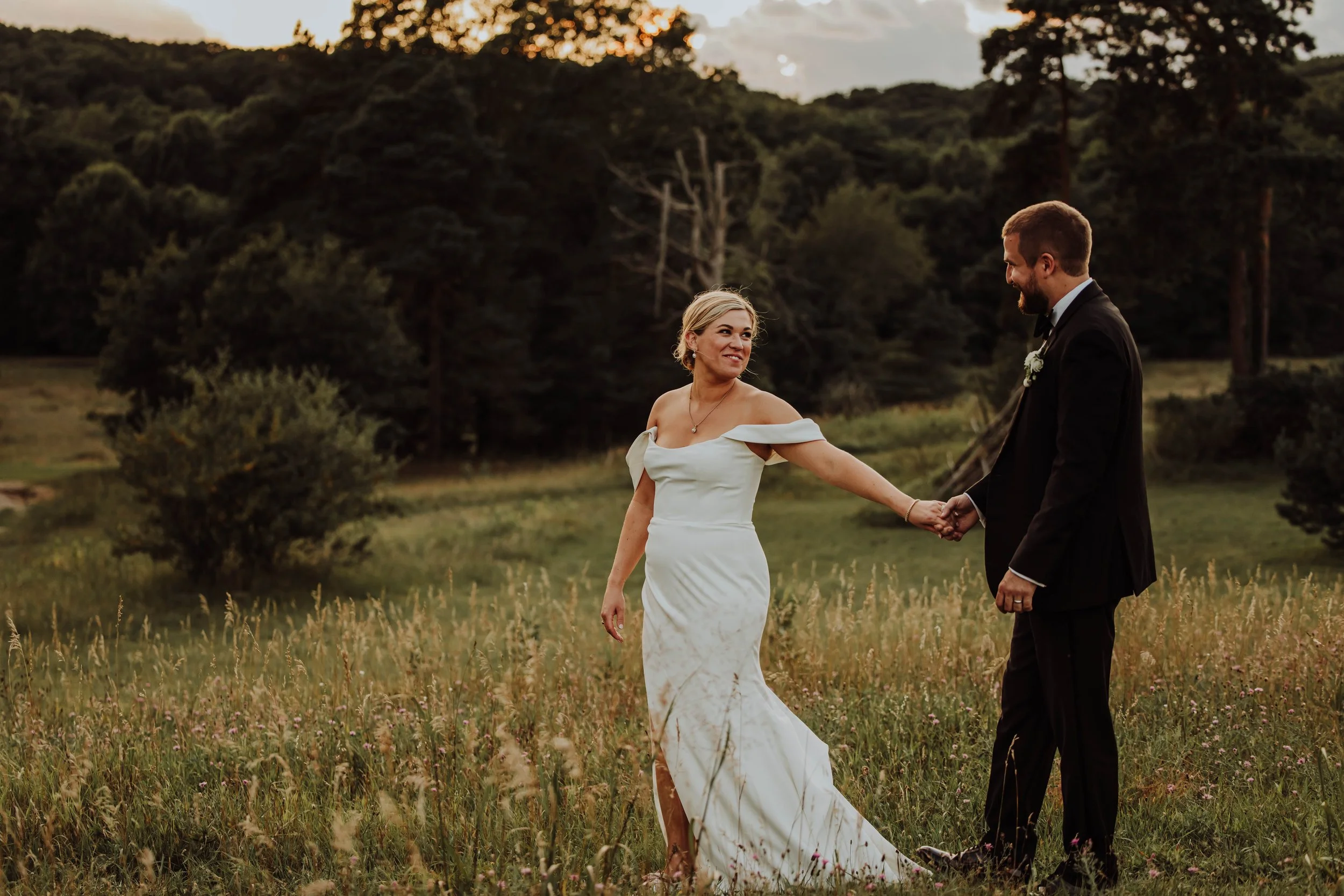 Bride and groom walking hand in hand through an open field at Felt Mansion Estates in Saugatuck Michigan