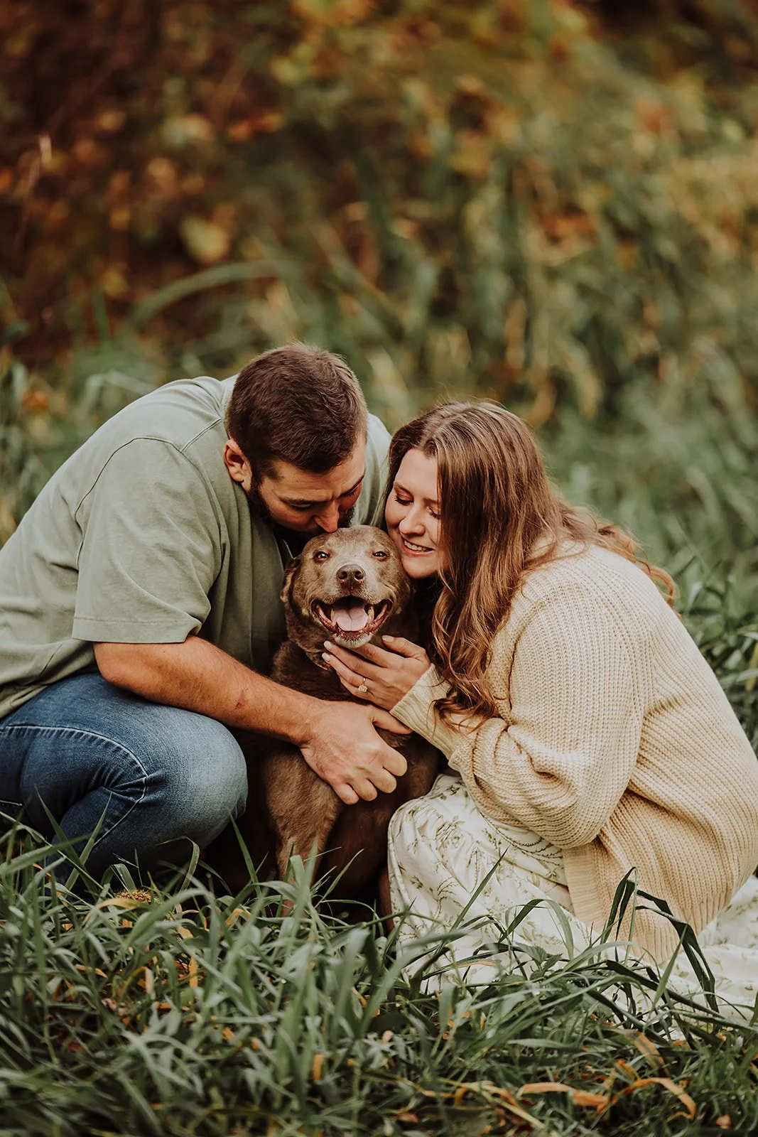 Engaged couple snuggling their dog in the grass, West Michigan engagement photographer