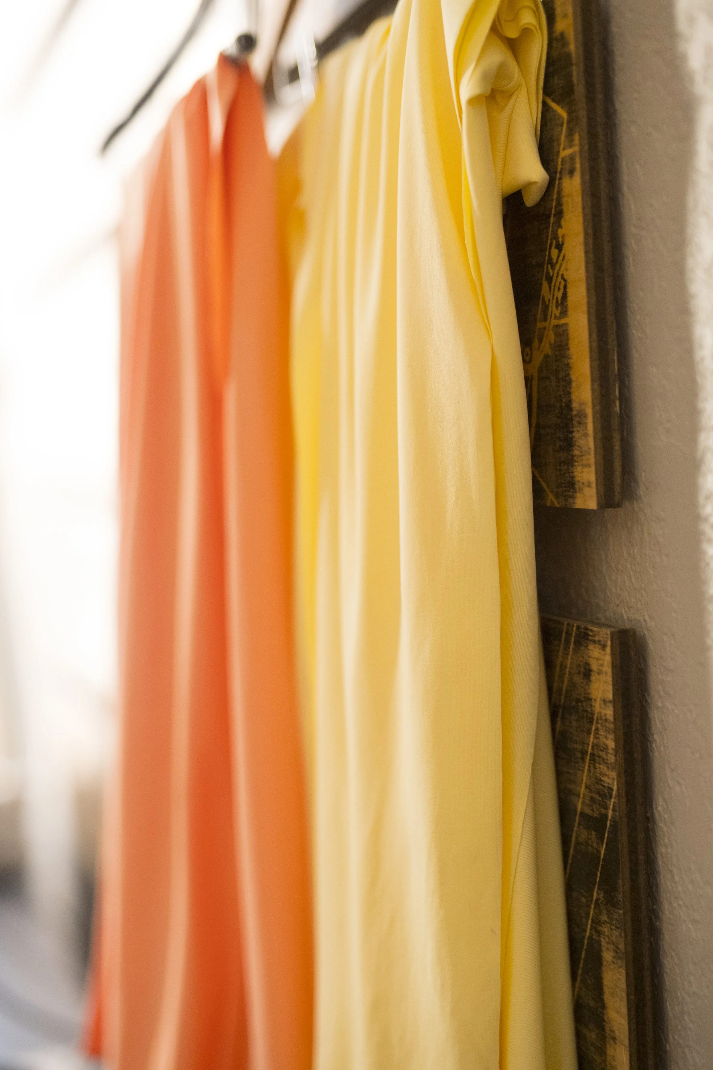 Close-up of colorful fabric rolls, including yellow, orange, and beige, stored on shelves.