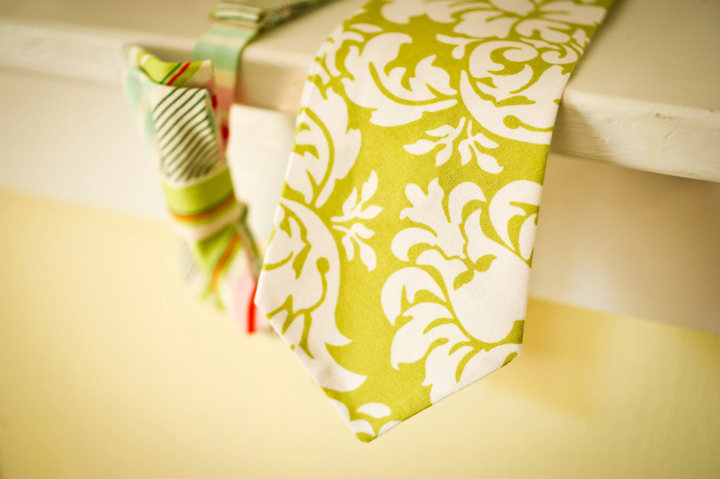 Close-up of a decorative fabric bunting with a green and white floral pattern, hanging on a cream-colored wall.