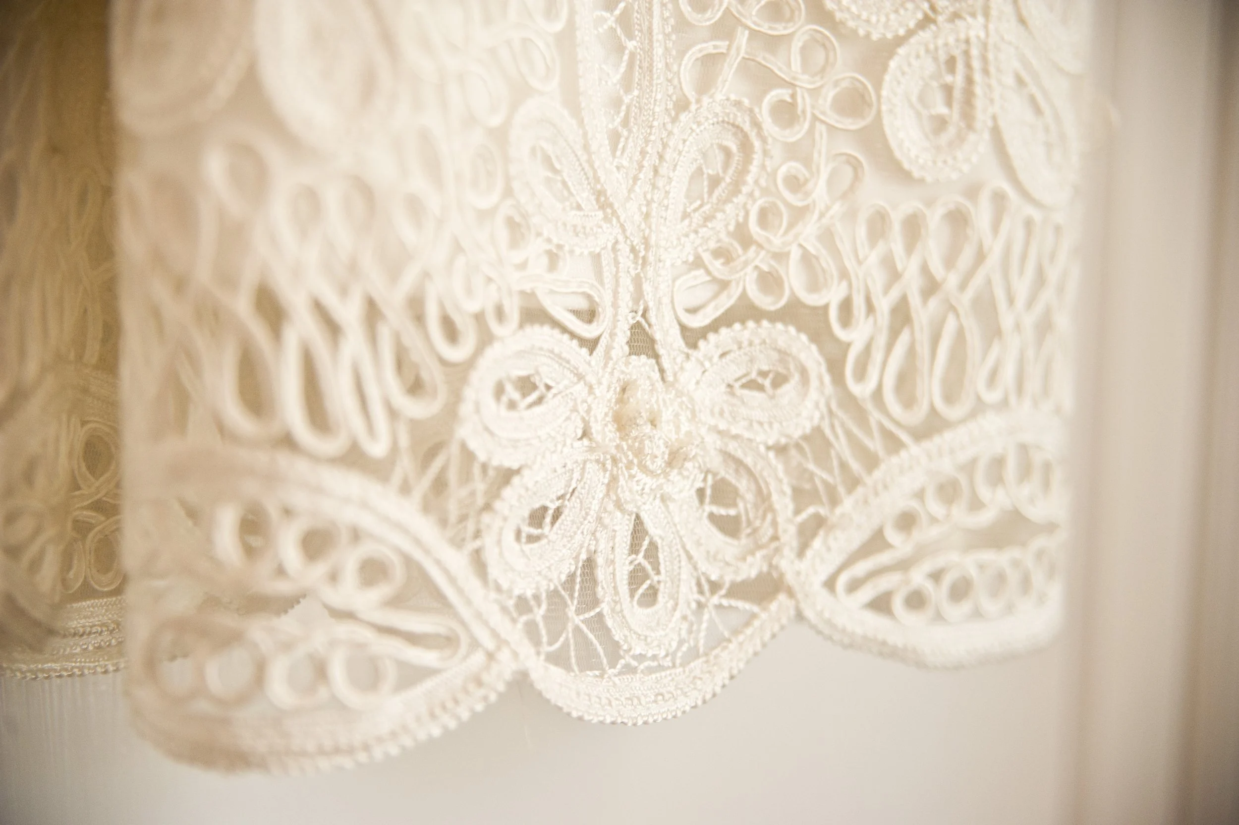 Close-up of intricate white lace fabric with floral and geometric patterns.