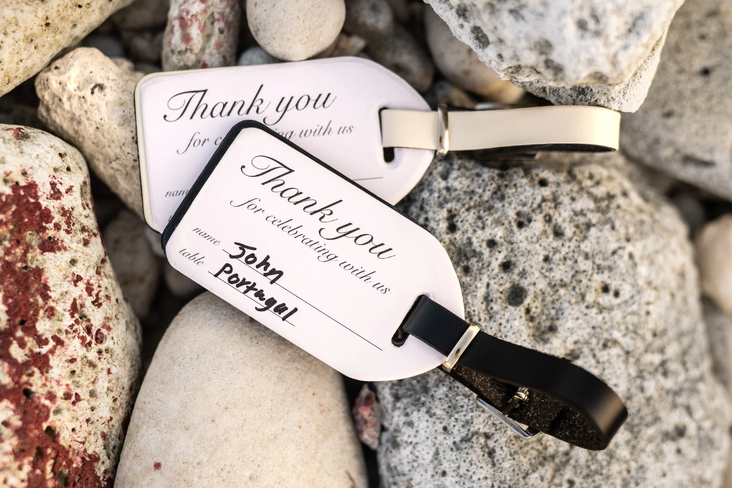 A wristwatch placed on a pile of rocks and stones, with tags that read 'Thank you for celebrating with us' and space for names and table numbers.