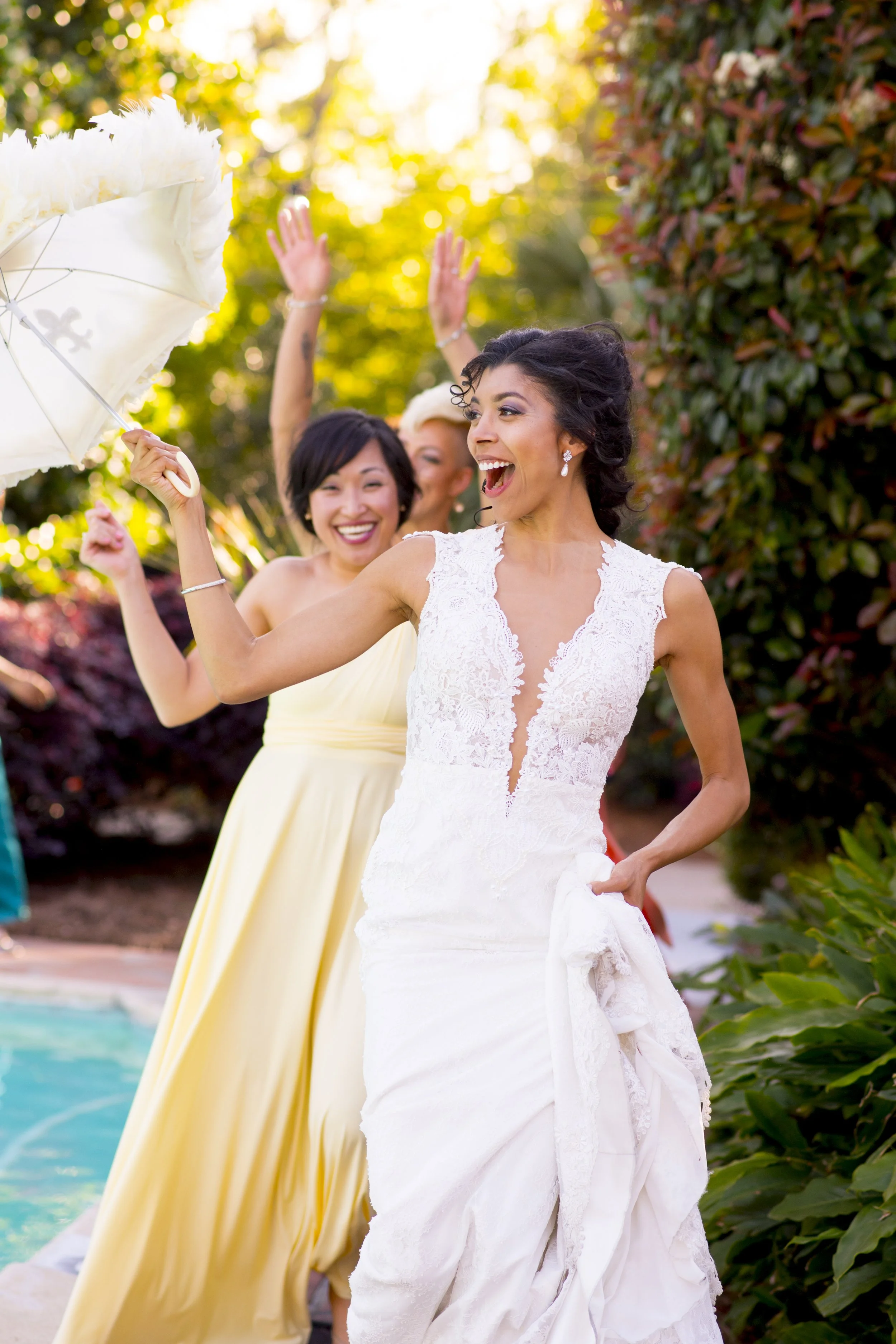 Women dancing outdoors near a pool during daytime, with trees in the background.