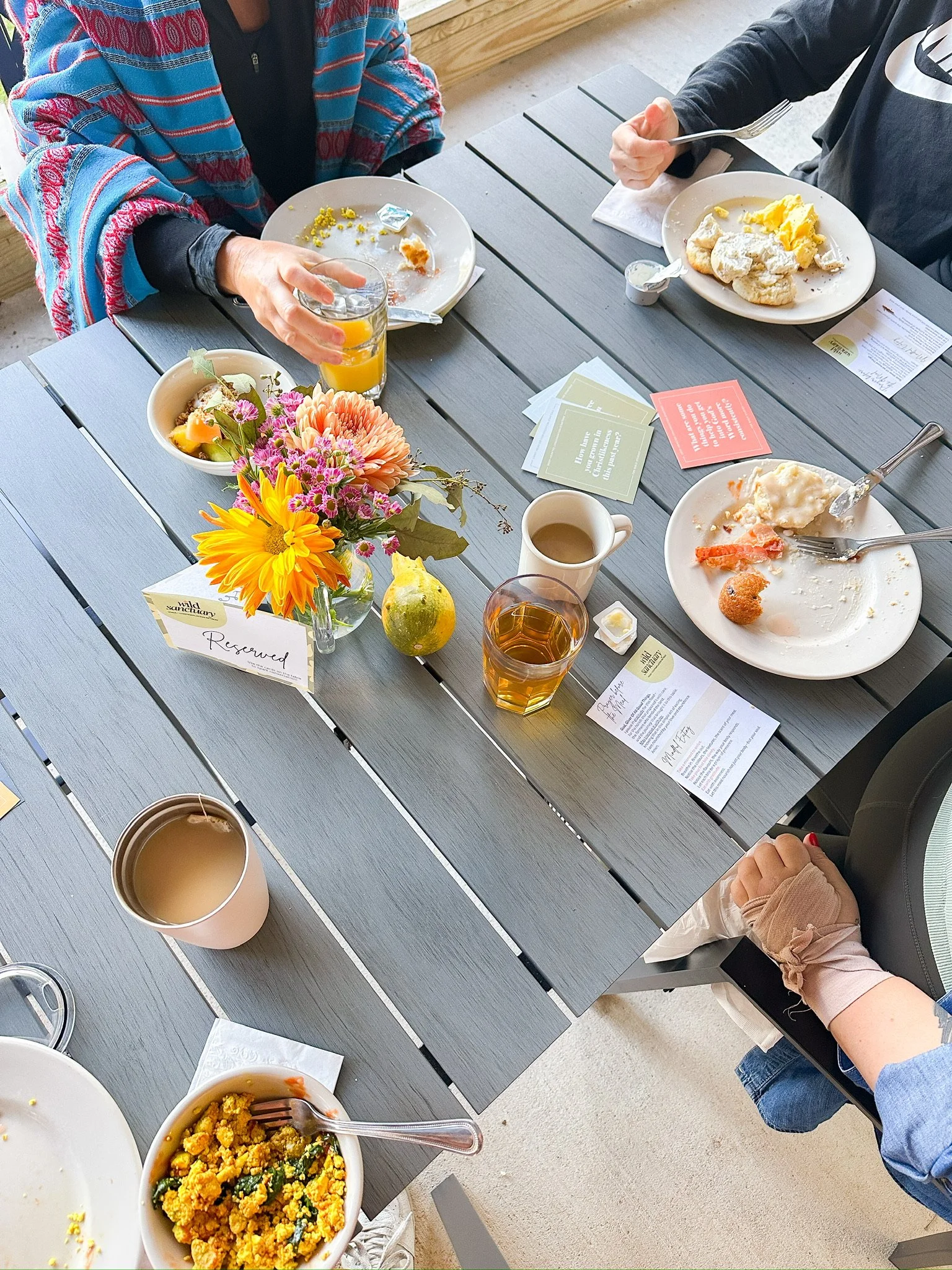 A breakfast table with plates of food, beverages, flowers, and a 'Reserved' sign, seen from above.
