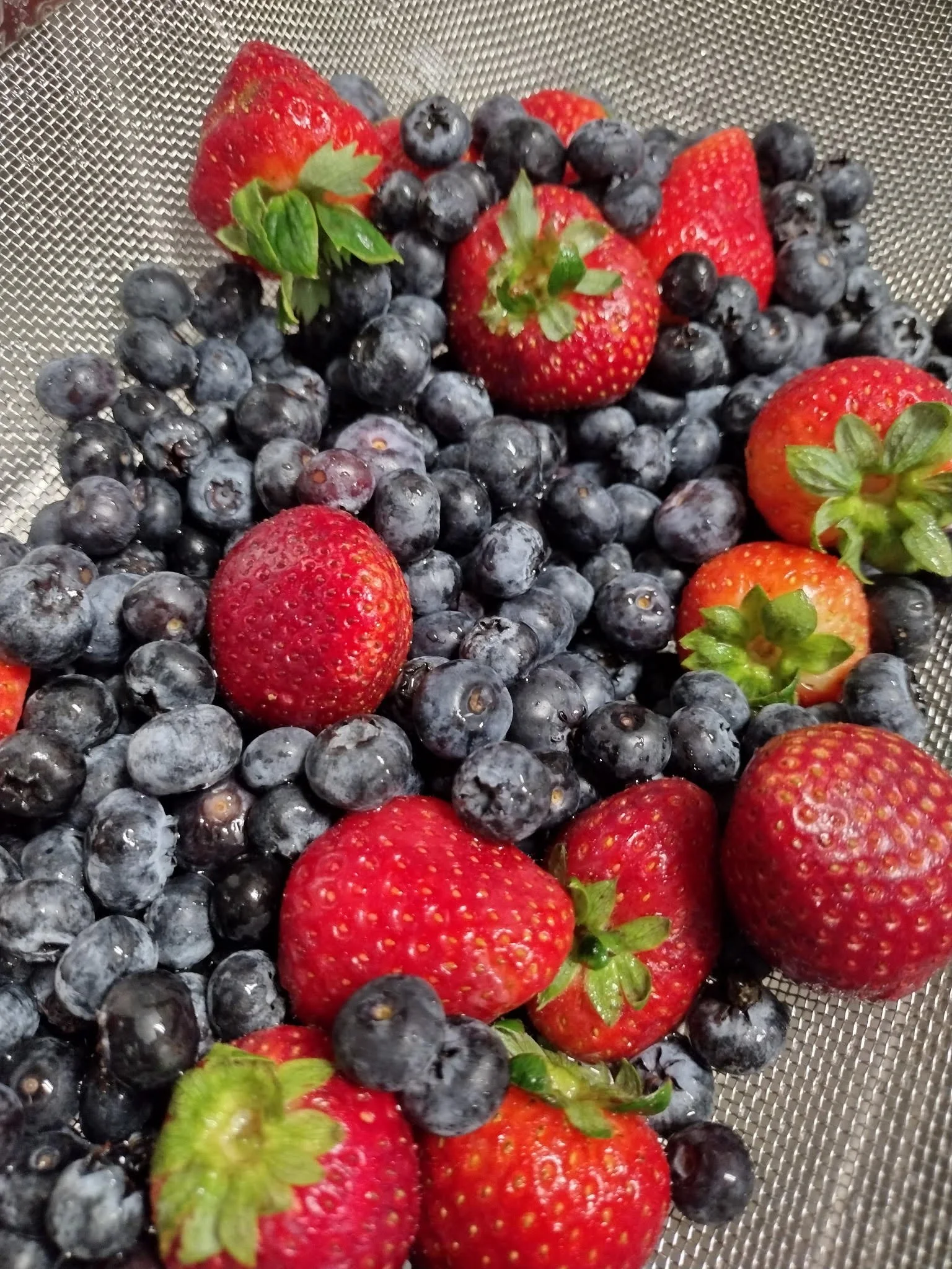 Fresh strawberries and blueberries on a metal surface