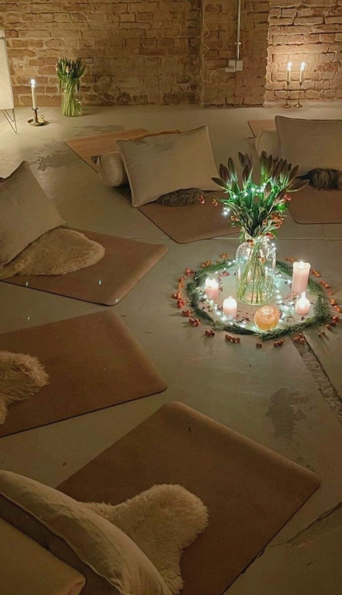 Cozy indoor setting with cushions, candles, flowers, and decorative lights arranged on the ground for a warm ambiance.