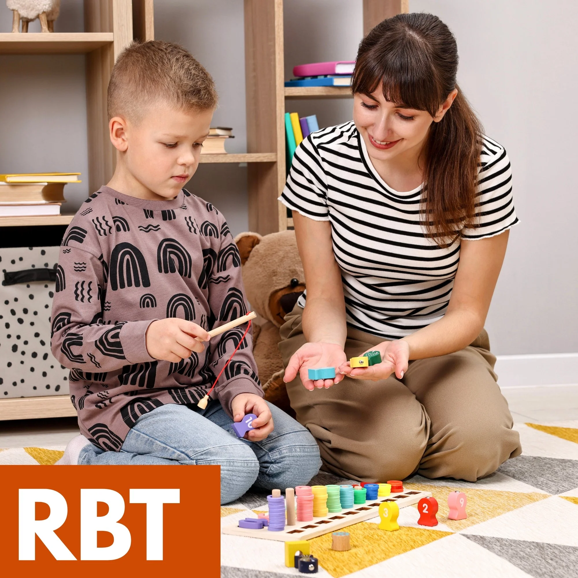 A woman and a young boy playing a colorful board game with counters, dice, and tokens on the floor in a cozy room with shelves and a stuffed bear in the background.