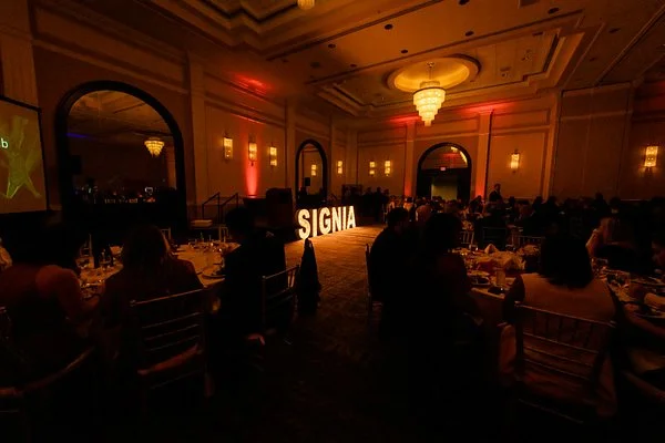 Corporate gala dinner in a ballroom with guests, event lighting and branded décor