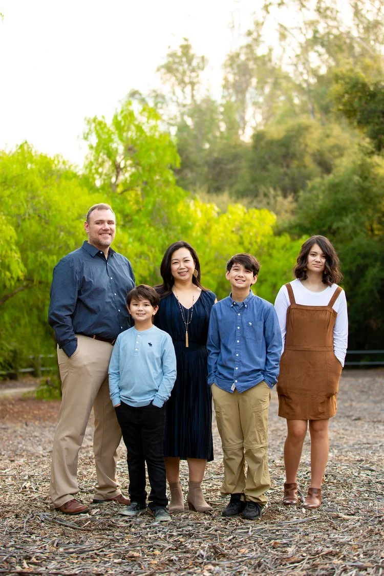 Two parents and their three kids stand to pose for a nice picture.