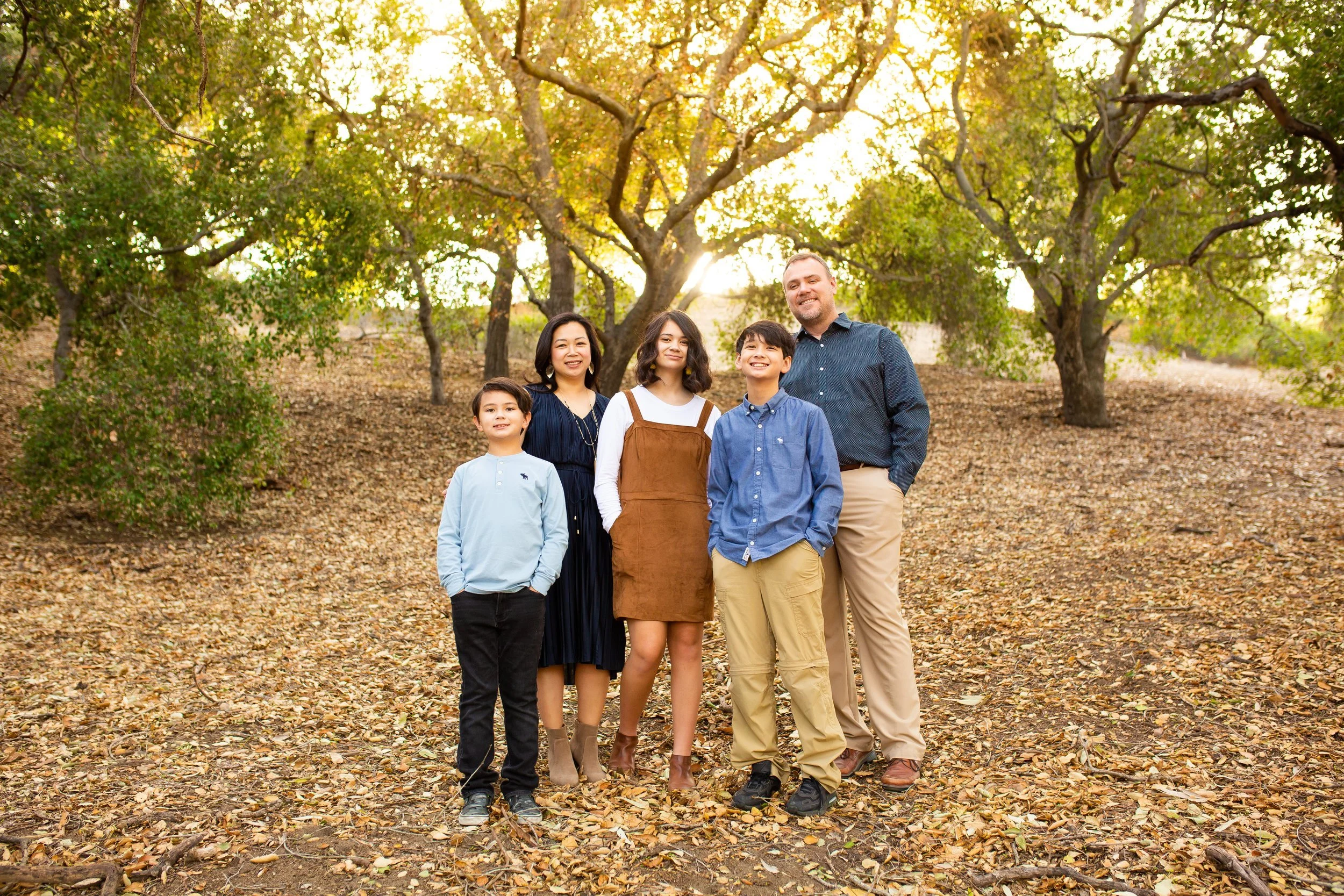 Parents and their three kids posing with their hands in their pockets.