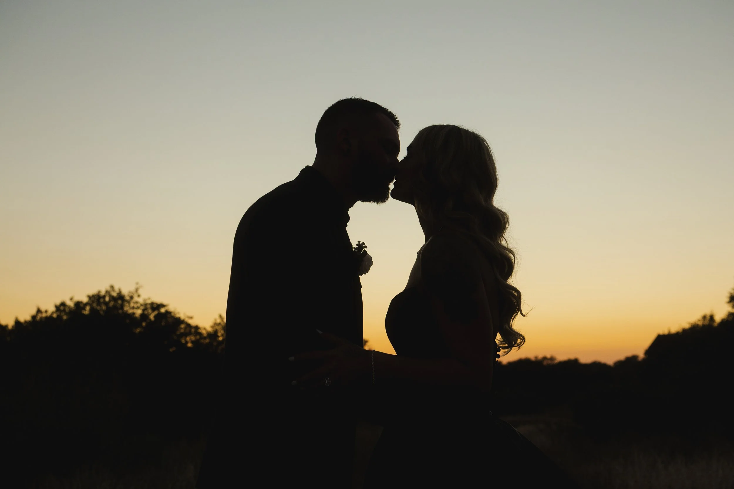Silhouette of a couple kissing at sunset outdoor.