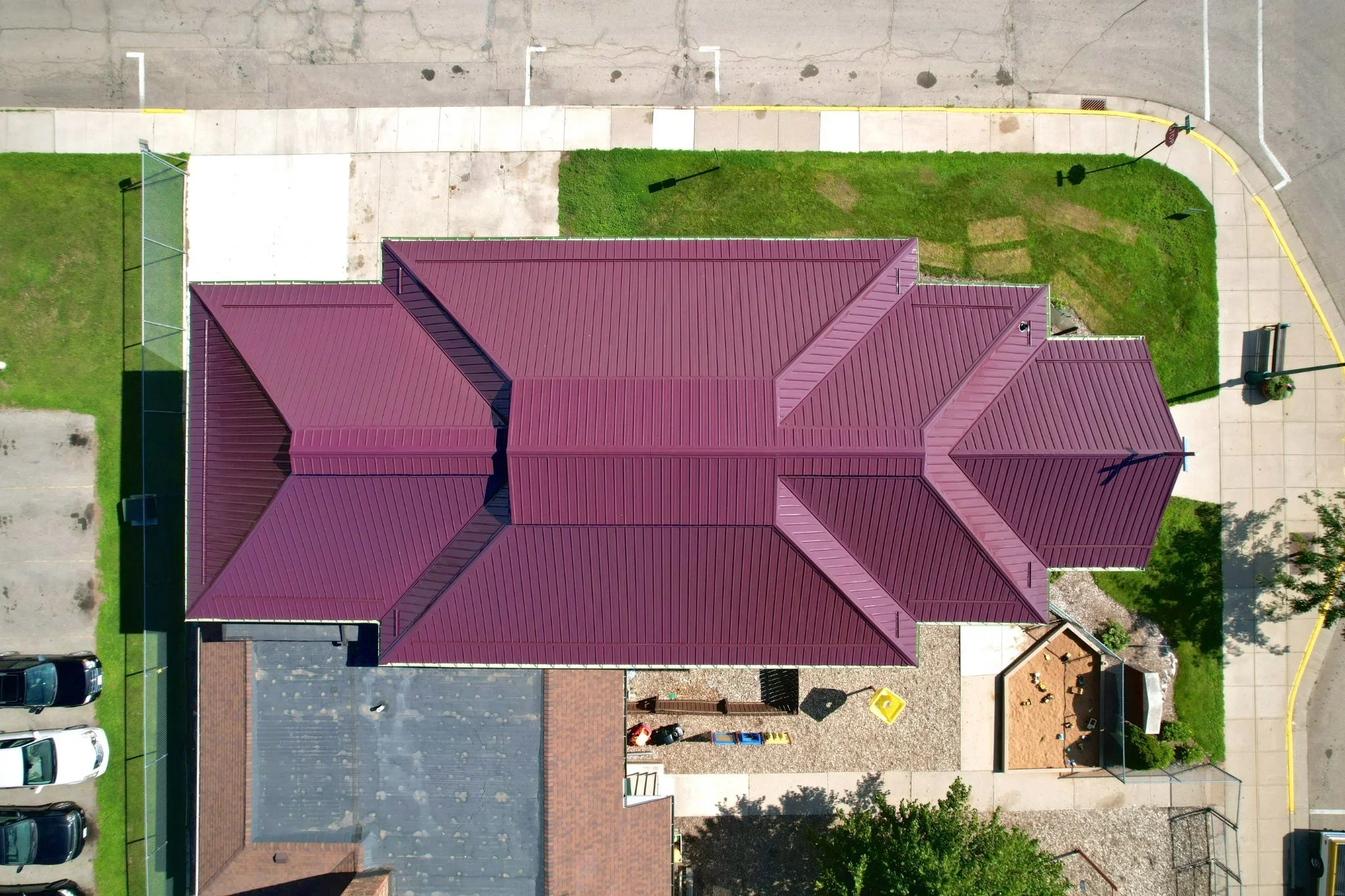 maroon red standing seam steel roof on commercial church buildiong with unique roof valley design