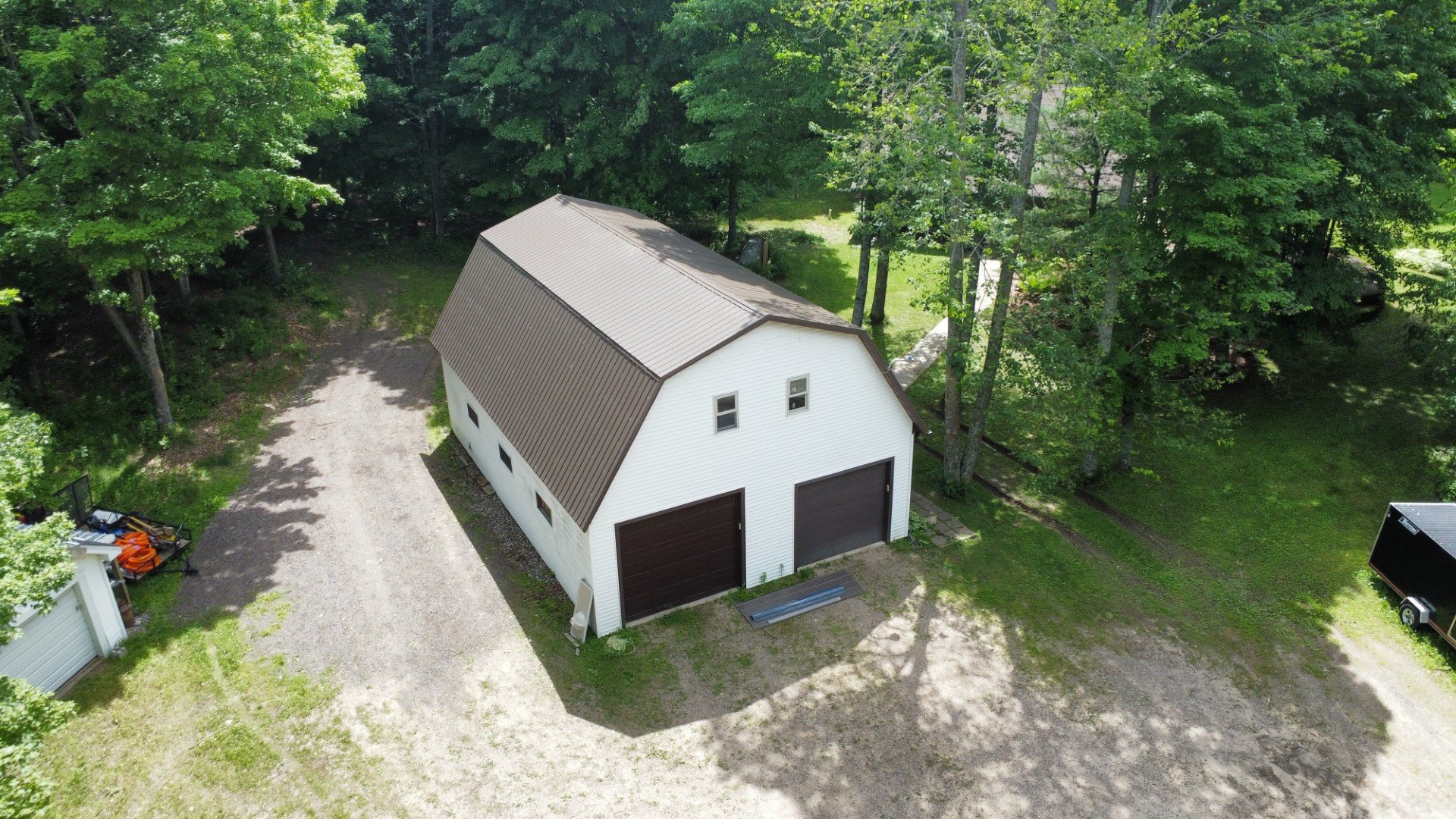 burnished slate standing seam metal roof with white siding and dark brown overhead garage doors