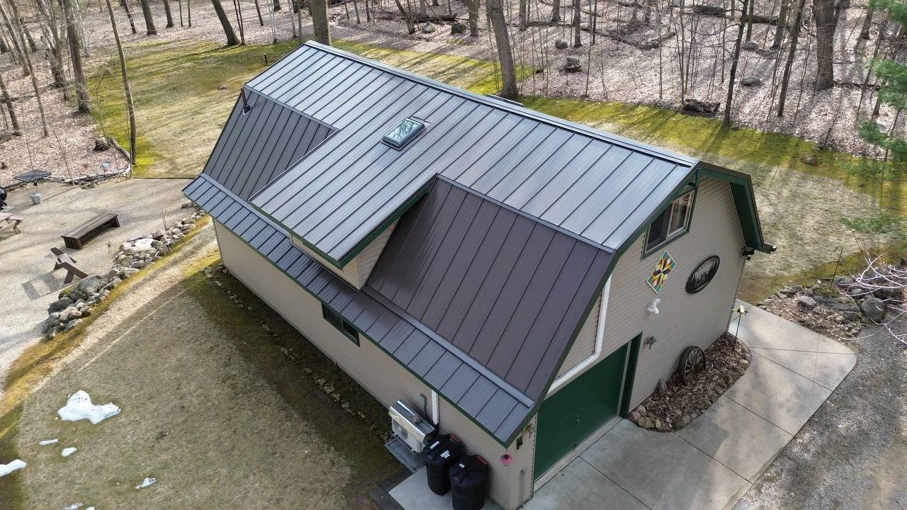 burnished slate standing seam metal roof on large shed in wisconsin with a green overhead grage door and green metal fascia and soffit accents