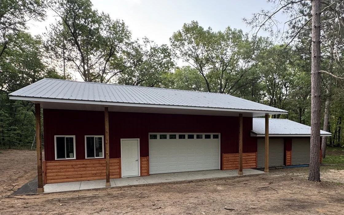 wooden cabin in the woods with a grey standing seam metal roof surrounded by tall trees