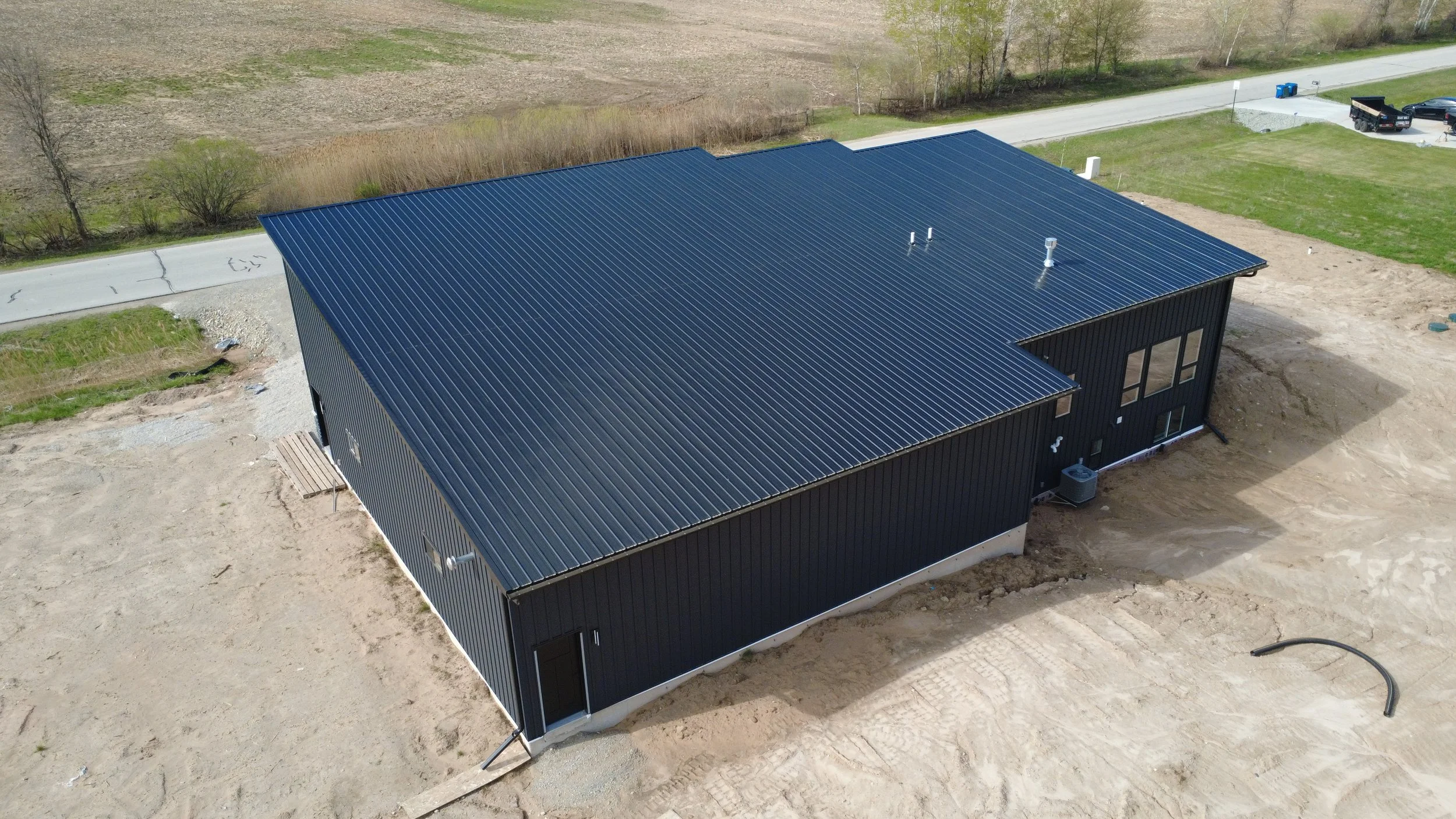 Black standing seam roof on black textured board and batten new construction home in residential area