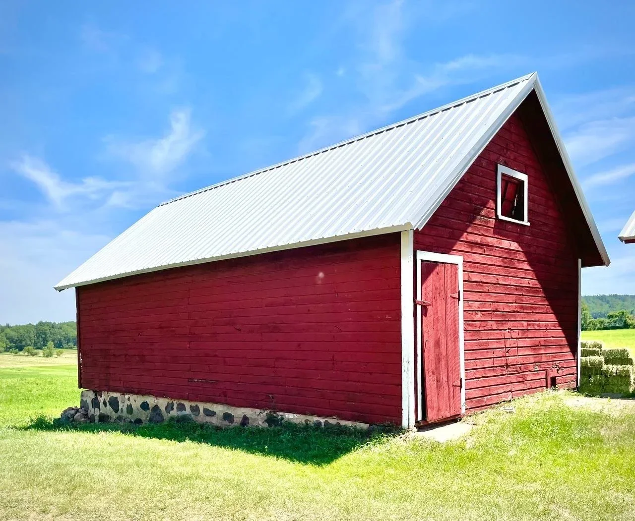 White standing seam roof on red wooden barn on a sunny day