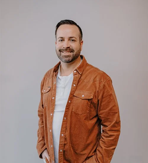 Man in a brown corduroy jacket poses against a plain background.