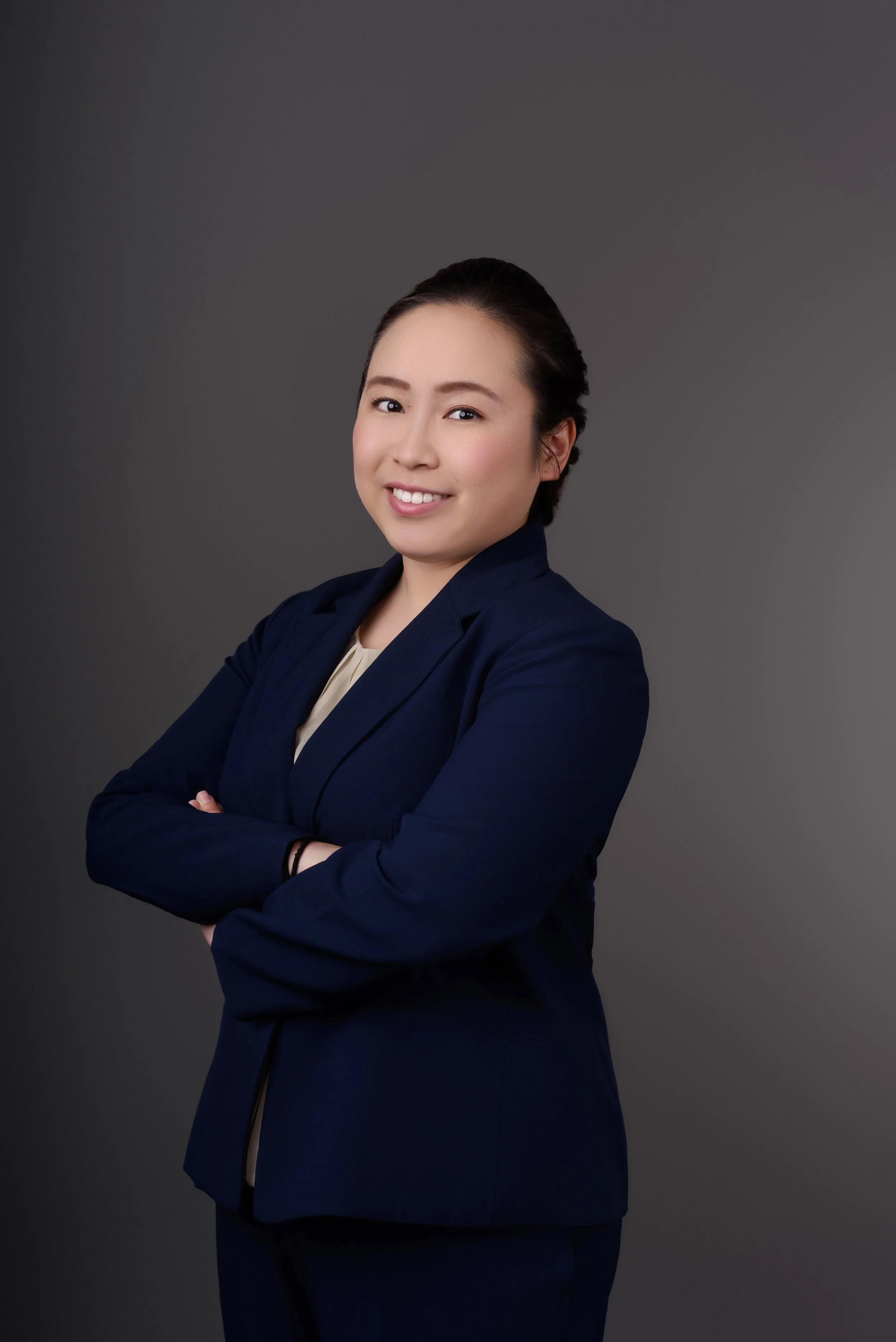 Tsukumo is smiling at the camera with her arms crossed