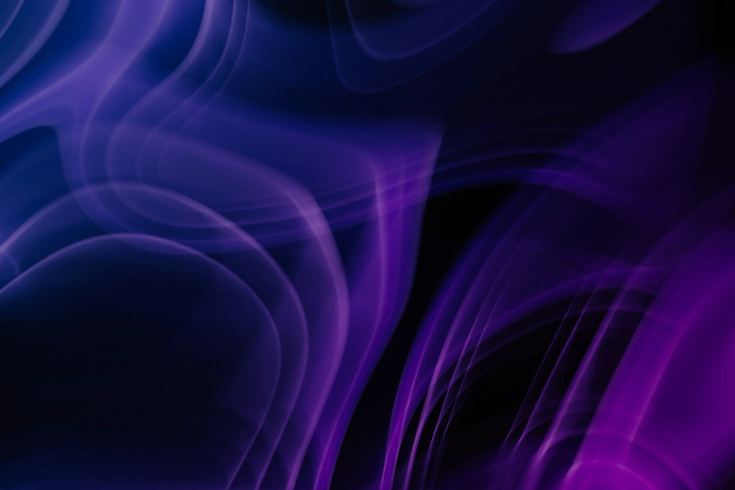 Abstract digital background with swirling purple and blue light streaks on a black backdrop.