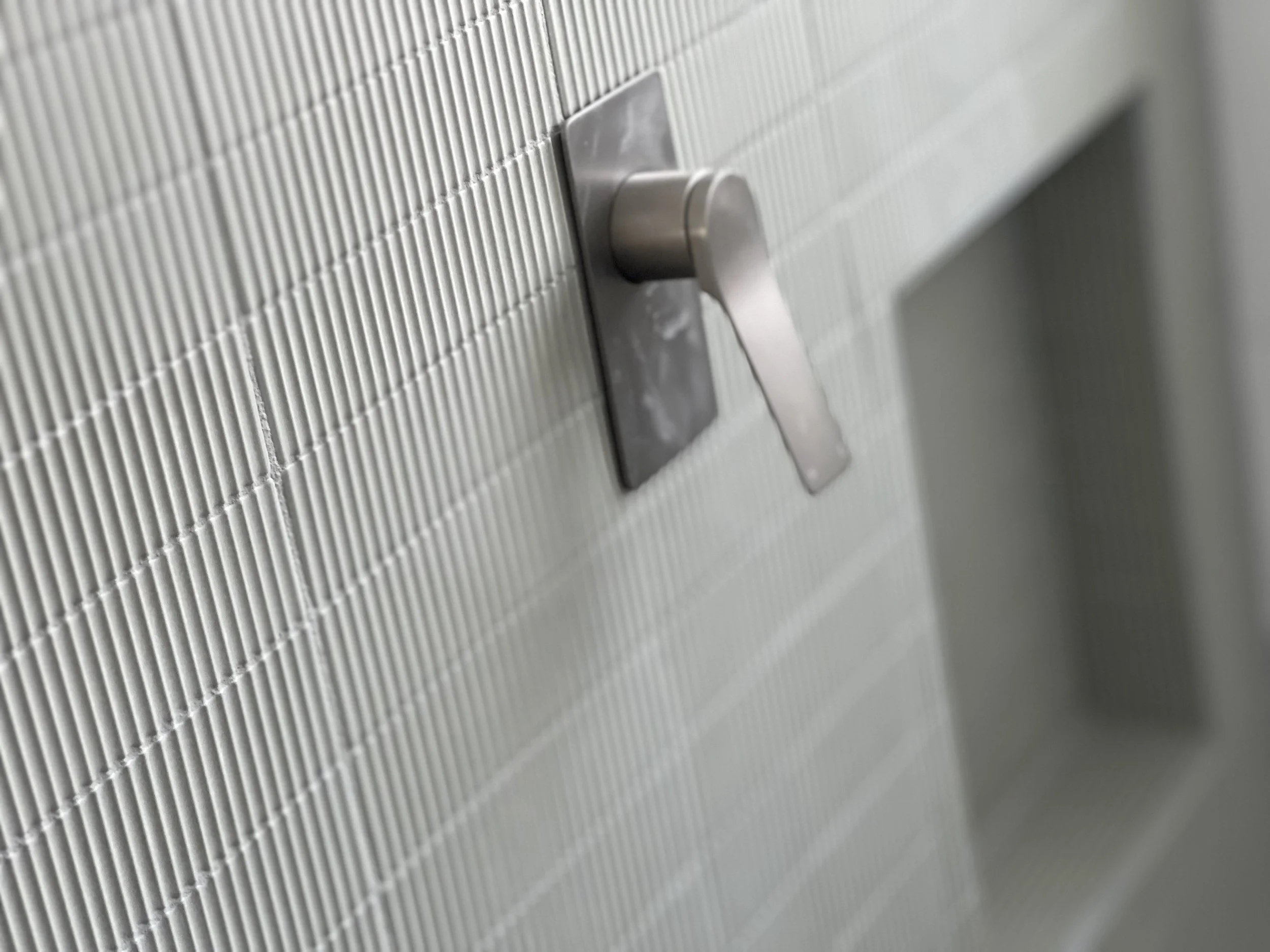 Close-up of a metal door latch handle on a textured metal surface.