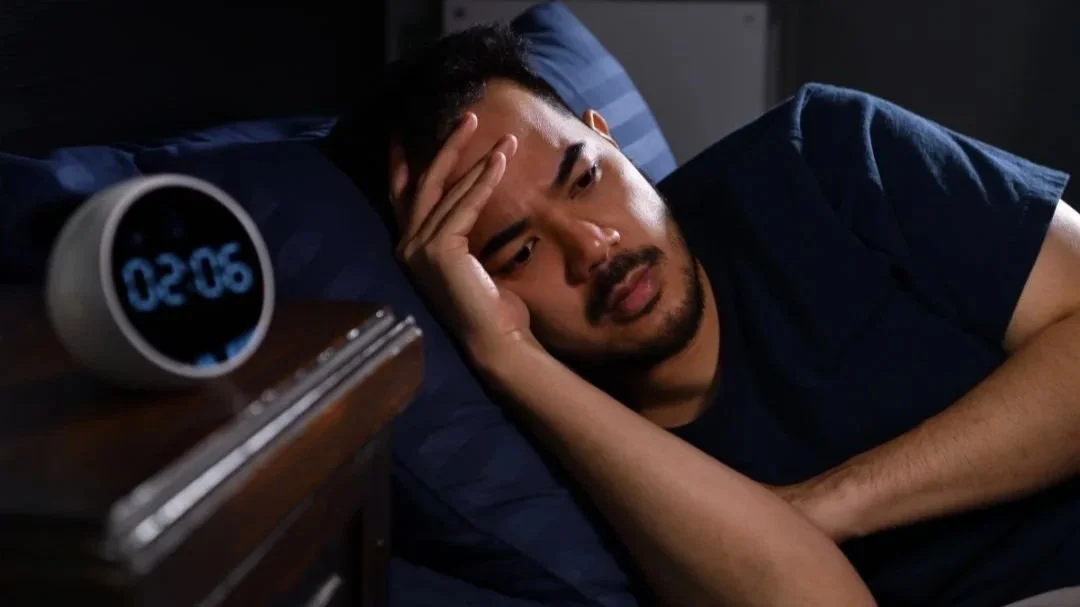 Person lying awake at night with racing thoughts, representing stress and anxiety-related insomnia treated with acupuncture in Calgary
