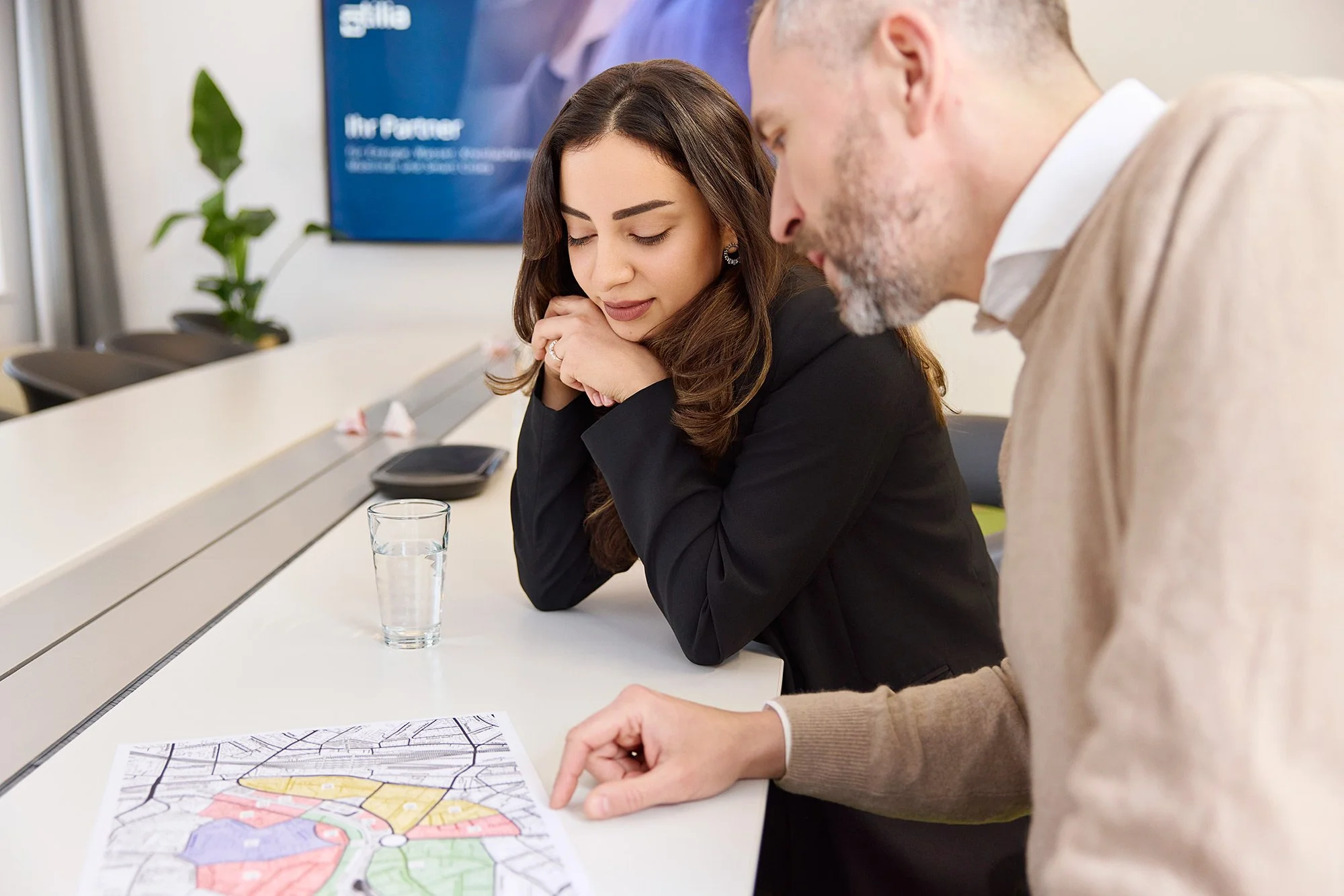 Ein Mitarbeiter erklärt seiner Kollegin etwas an einem Lageplan